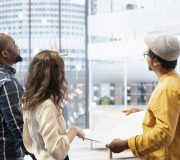 Business clients and broker salesman examining blueprints and layout during an office tour, planning leasing contract and investment strategy for startup development. Office hunt.